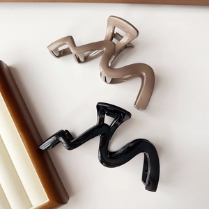 Detailed view of wave-shaped hair clips in black and khaki colors with smooth finish