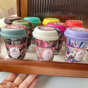Close-up of colorful rubber bands in decorative jars with vintage floral labels