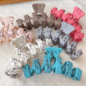 Collection of oversized matte wave hair claws in diverse pastel colors with ink splatter detail