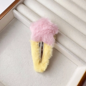 Détail d'une pince à cheveux étoile en peluche rose et jaune sur plateau velours
