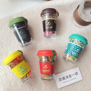 Detail of five mini drink cups containing colorful hair elastic bands on plush background