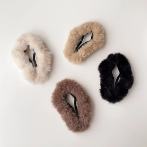 Dettaglio di quattro fermagli per capelli in peluche a stella in beige, kaki e nero