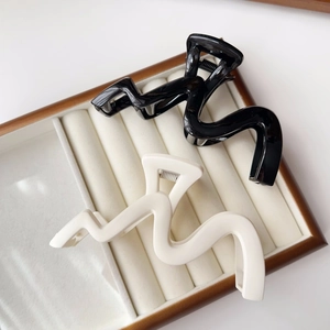 Detail view of wavy hair clips in black and cream white on a velvet display tray