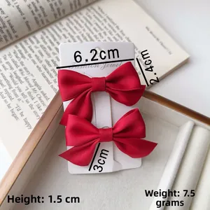 Detailed view of two red satin bow hair clips on card with 6.2cm size measurements