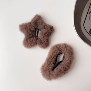 Dettaglio di fermagli per capelli in peluche marrone a forma di stella su sfondo bianco