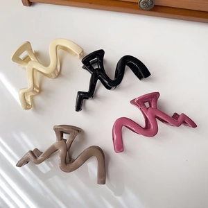 Flat lay showing wave-shaped hair clips in cream, black, pink, and mocha brown colors