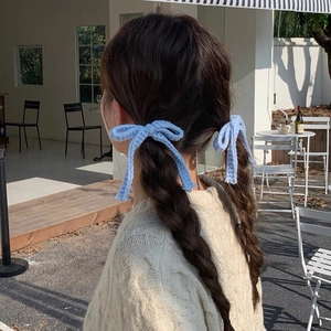 Details von hellblauen gestrickten Schleifen-Haarbändern mit langen Bändern am Zopf
