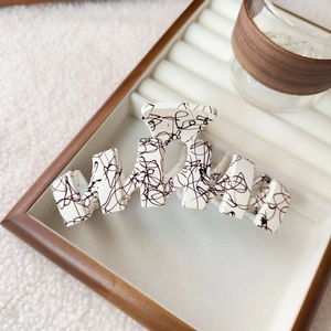 Detail of artistic cream hair claw with black scribble pattern on jewelry tray