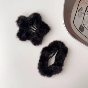 Dettaglio di due fermagli per capelli in peluche nero, forme a stella e ovale su bianco