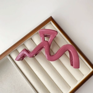 Macro detail of dusky pink wavy hair claw clip on white velvet jewelry display