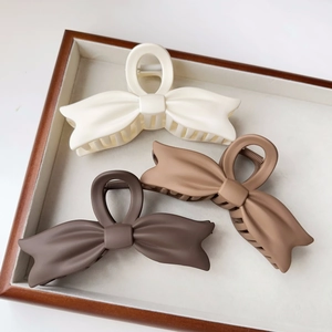 Macro view of matte large bow hair claw clips in beige, light brown, and dark brown colors