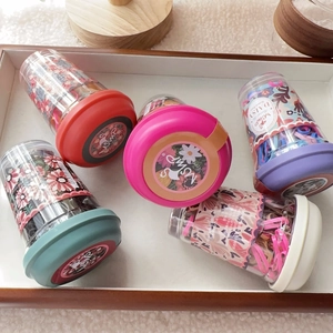 Set of colorful disposable hair ties in transparent jars on a white wooden tray