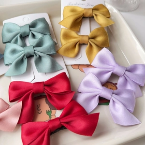 Detailed view of colorful satin bow hair clips set on a ceramic tray display