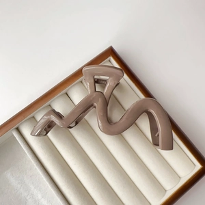 Detailed macro view of a mocha brown wavy hair claw clip resting on a velvet jewelry box