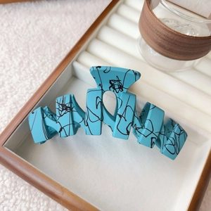 Detail of matte sky blue large claw clip with black abstract wave graffiti pattern