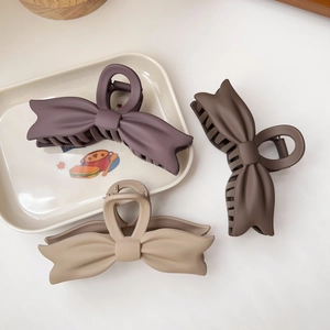 Detailed view of matte bow hair claws in elegant mauve, coffee and beige colors