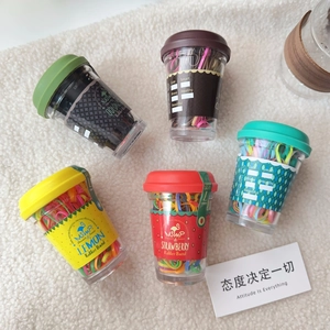 Close-up of candy-colored elastic hair bands in various coffee cup storage containers