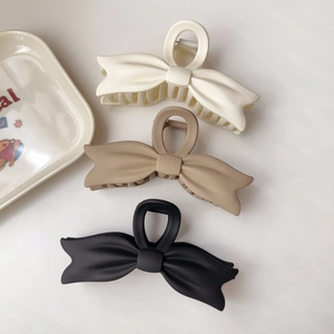 Three elegant bow hair clips in white, khaki and black colors for women's hairstyling