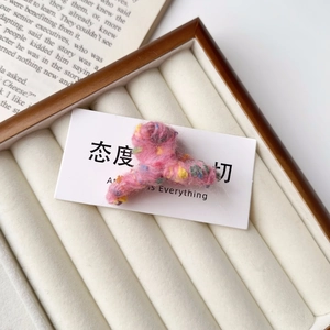 Détail de la mini pince à cheveux en peluche rose avec des pois colorés sur carte blanche