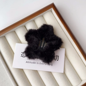 Dettaglio macro di un fermaglio per capelli a stella in peluche nero su vassoio in legno