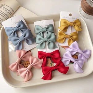 Set of 2 satin bow hair clips in various colors organized on a fashion display card