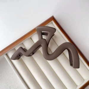Detail view of the large dark brown wavy hair claw clip with matte finish and metal spring