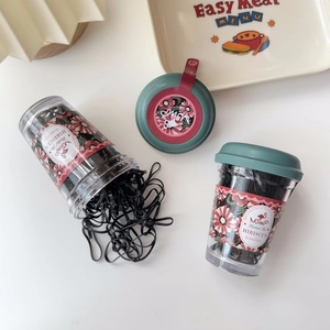 Detail of black elastic hair bands in transparent cup with vintage floral label