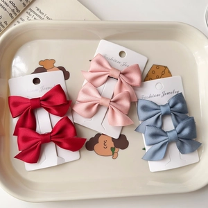 Detail of satin bow hair clips set in red pink and blue on a white display card