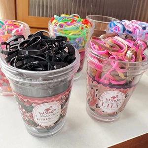 Jar of candy-colored disposable elastic hair ties with aesthetic botanical labels