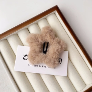 Dettaglio del fermaglio a stella in peluche color albicocca su espositore in velluto