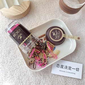 Detail of candy color elastic hair bands spilling from transparent bottle onto tray