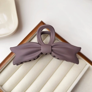 Macro detail of a large matte purple bow hair claw clip with elegant resin texture
