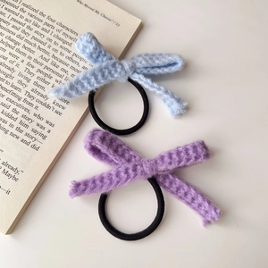 Blaue und lila gestrickte Schleifen-Haargummis mit Gummiband auf weißem Grund