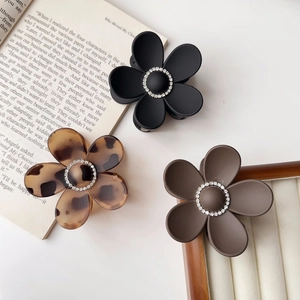 Detailed view of matte flower hair claws in black, brown and leopard with rhinestones