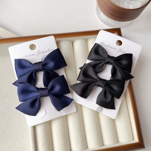Detail of navy blue and black satin bow hair clips on jewelry display card