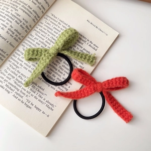 Detailansicht handgestrickter Haargummis mit Schleifen in Grün und Orange auf Buch