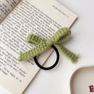 Detailansicht eines matcha-grünen Häkelbogen-Haargummis auf einer offenen Buchseite