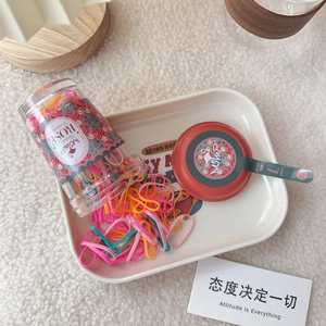 Close-up of candy-colored elastic hair ties in a vintage-style clear bottle on a tray
