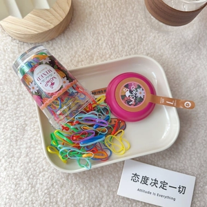 Close-up of 130pcs colorful mixed elastic hair bands stored in a clear cylinder container