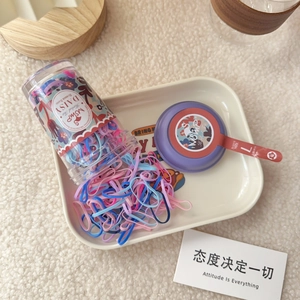 Detailed view of colorful elastic hair bands in a floral jar with a purple lid and red hook