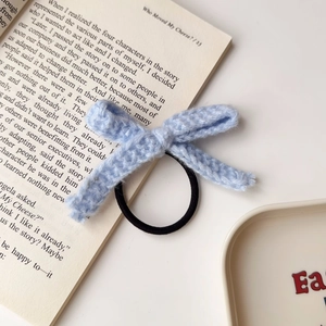 Detailierte Textur des blauen gehäkelten Haargummis auf einem offenen Buch im Licht