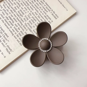 Close-up of matte chocolate brown flower hair claw clip with central rhinestone detail