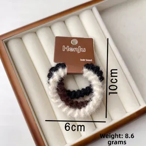 Dettaglio degli elastici per capelli in peluche lavorato a maglia nei colori nero e crema
