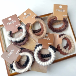 Dettaglio di elastici per capelli in maglia peluche nei toni della terra su carta