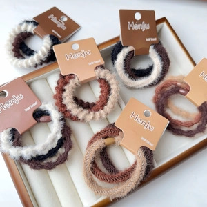 Dettaglio di elastici per capelli in peluche dai toni caldi su vassoio espositivo