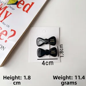 Gros plan d'une paire de barrettes à nœud en acétate noir sur une carte blanche