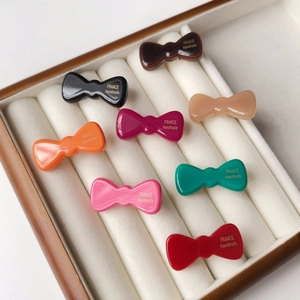 Huit couleurs de barrettes noeud en acétate présentées dans un écrin de bijoux