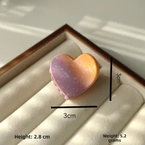 Macro view of 3cm gradient purple and orange heart hair claw with polka dot patterns