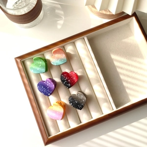 Close-up of heart-shaped gradient hair claws with speckled finish in a jewelry tray