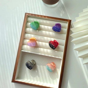 Close-up of six heart-shaped gradient hair clips with star-dot texture in a wooden tray